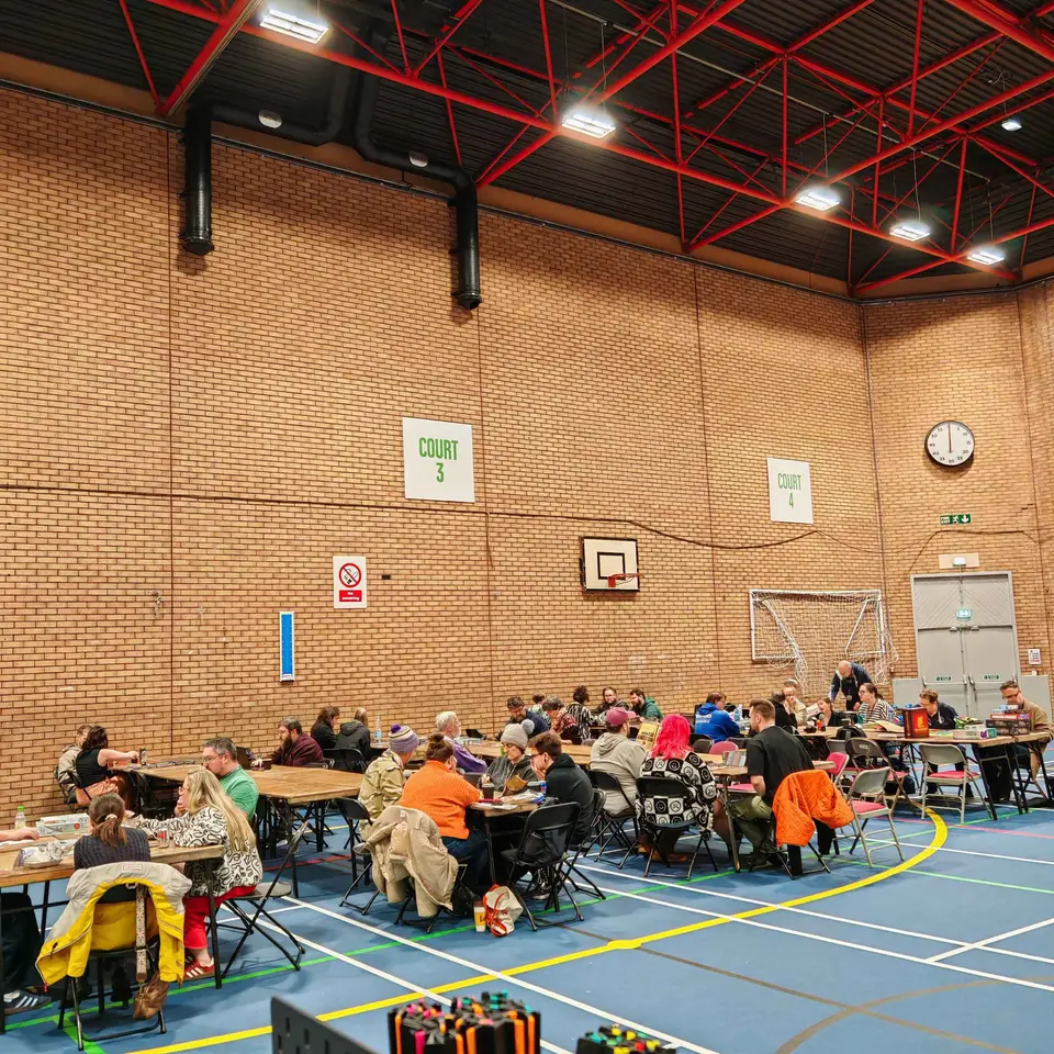 A packed hall of tables with people playing games